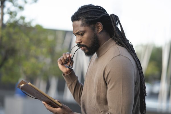 African American man, with dreadlocks, and spectacles, reading a book at sunset